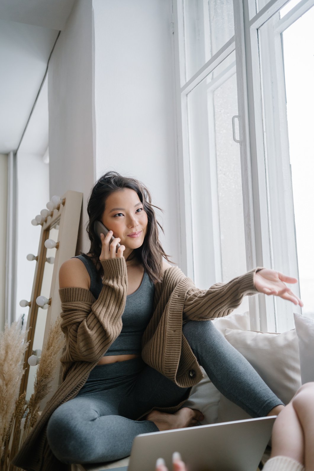 Woman talking on Phone seated beside Window Pane 